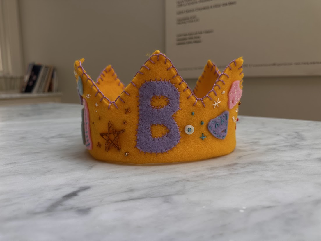 Golden yellow felt crown with a purple B and stars
